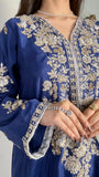 Detailed close-up of a model's hands over the heavily worked V-neck bodice of a royal blue pakistani festive wear outfit.