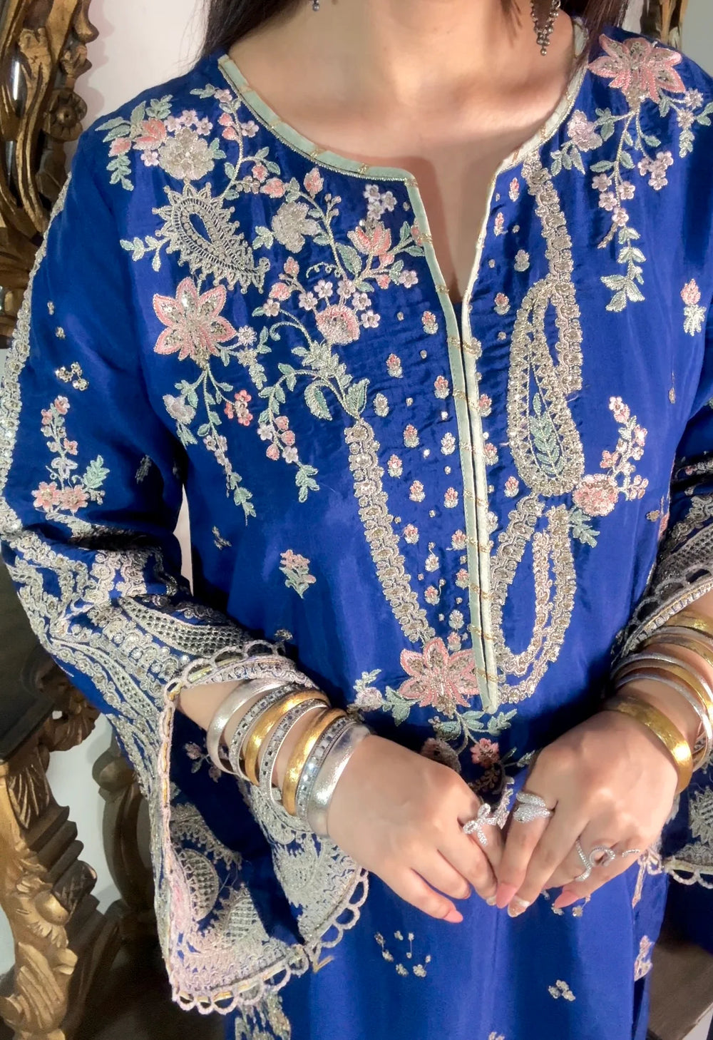 Model wearing embroidered blue kaftan suit showing floral embroidery detail at the neckline