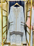 Light blue embroidered gHARARA dress hanging on a rack with floral patterns in the background