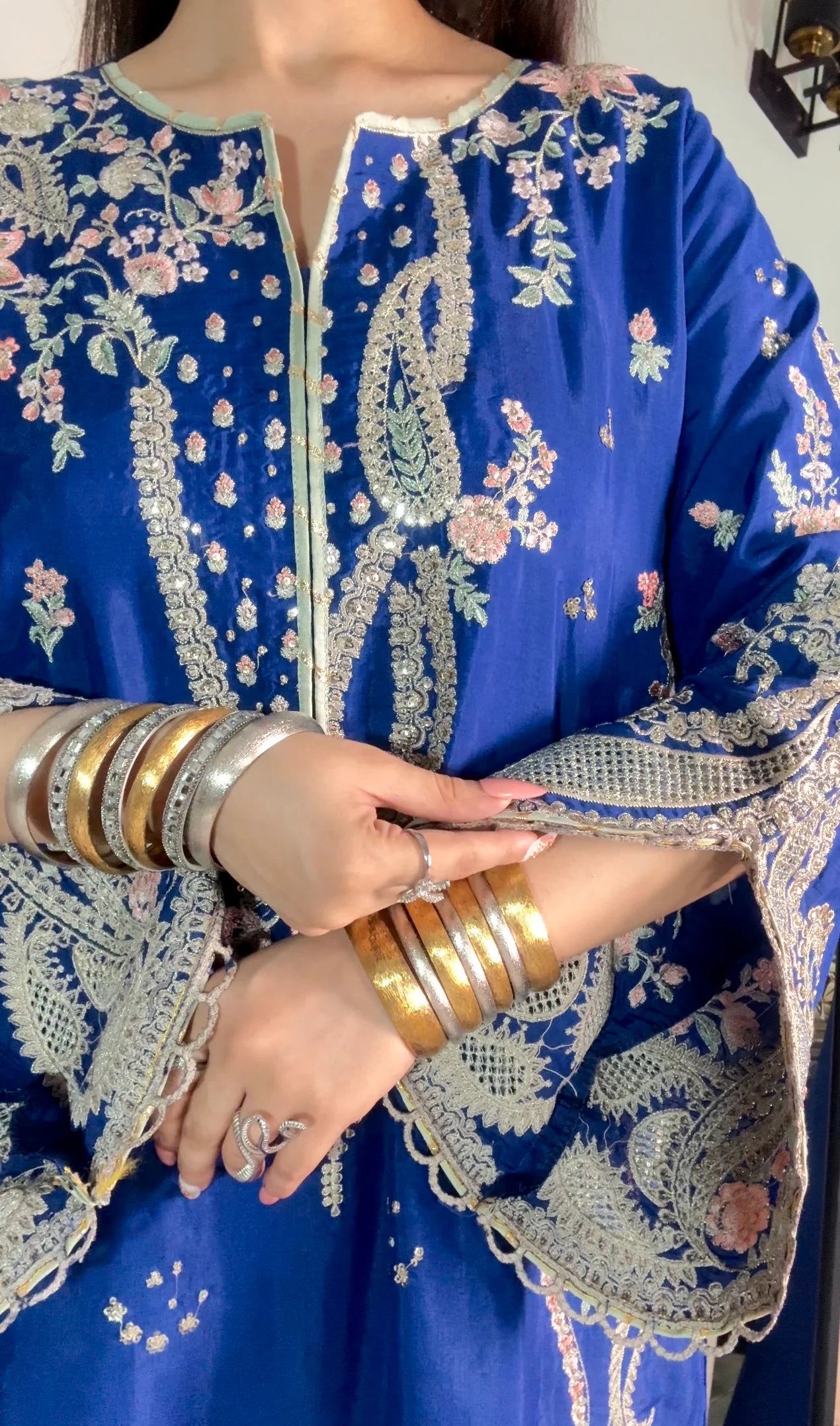 Close-up of royal blue silk kaftan suit with gold and silver zari embroidery and layered bangles
