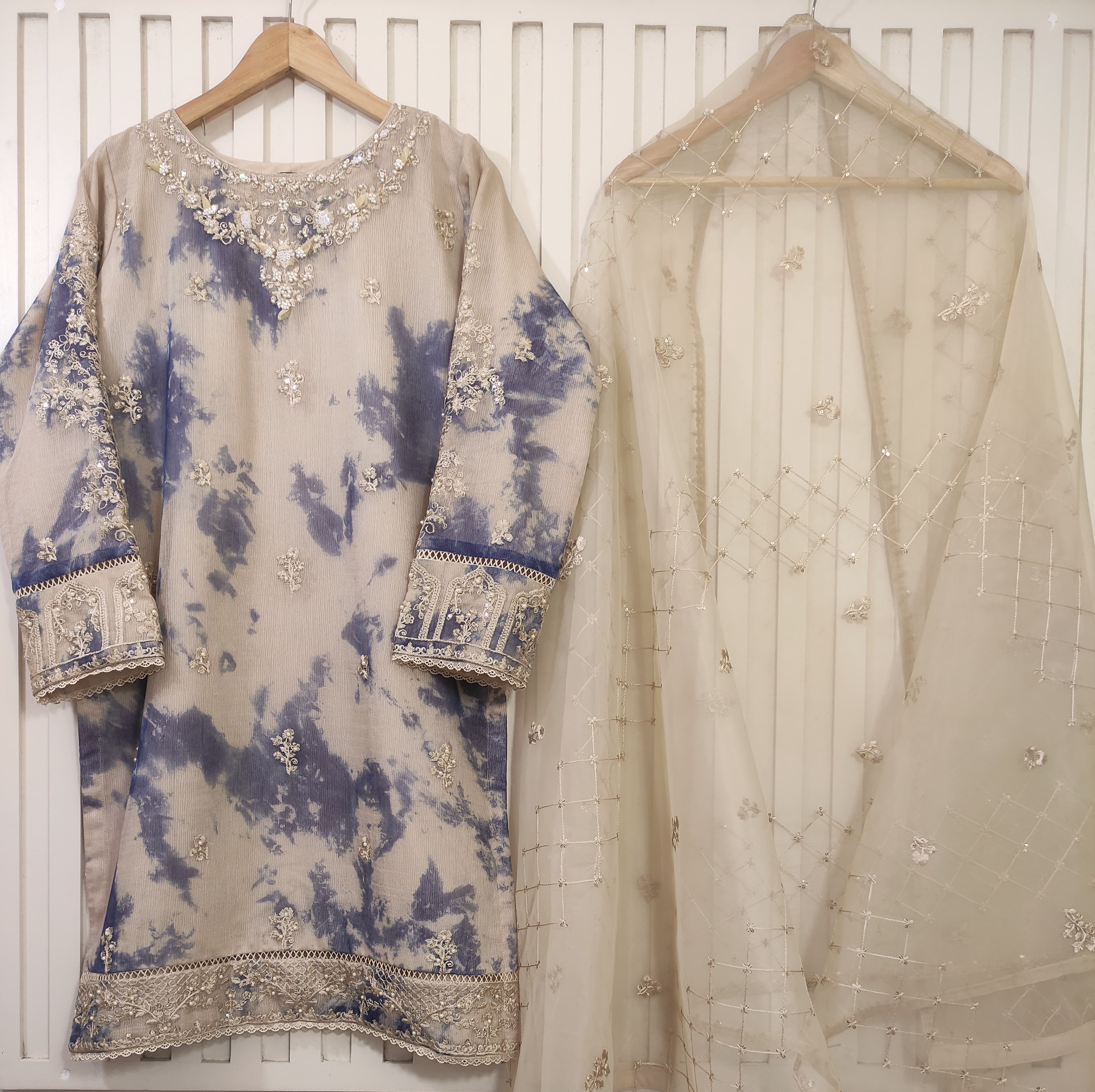 Traditional embroidered outfit with a blue and beige pattern on a white background