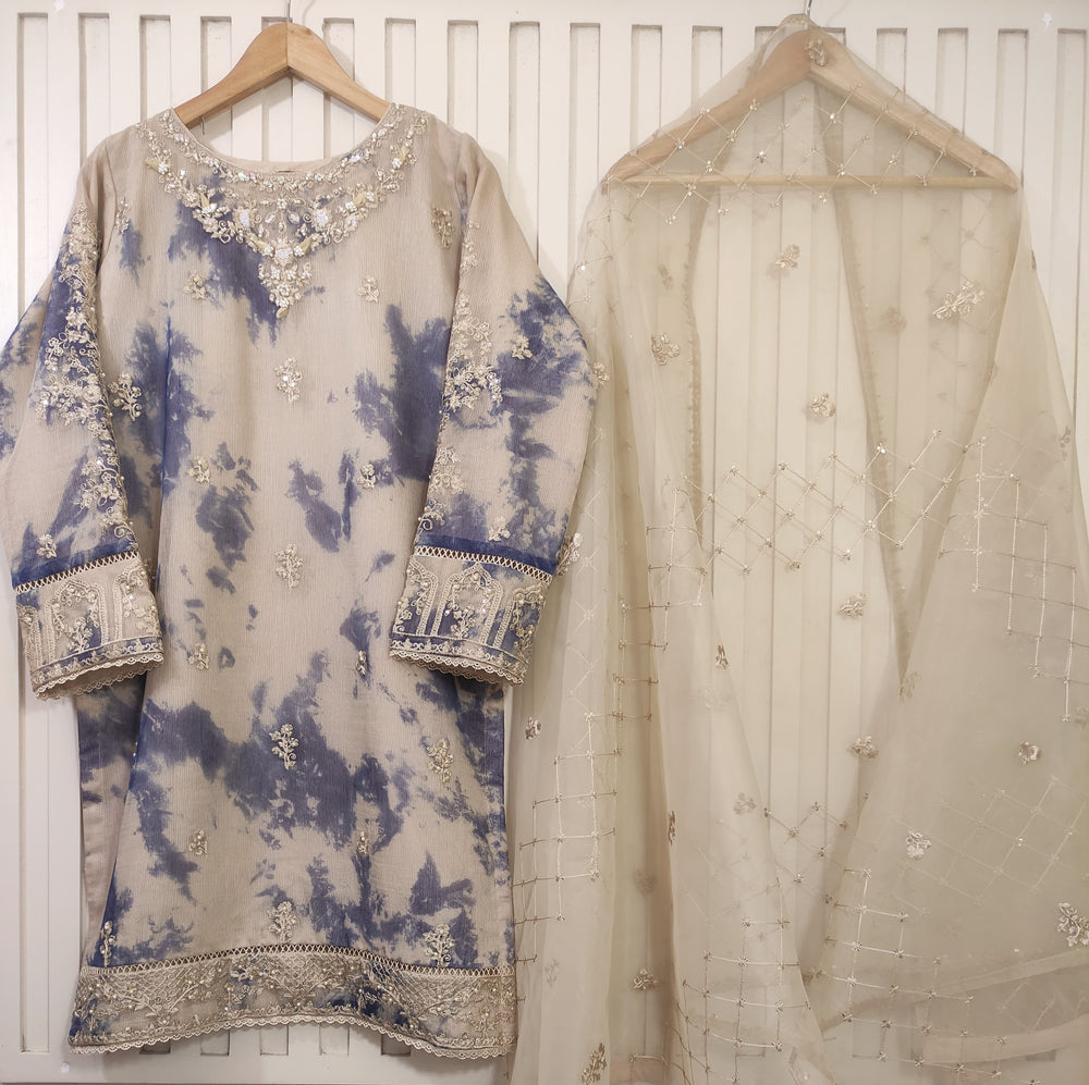 Traditional embroidered outfit with a blue and beige pattern on a white background