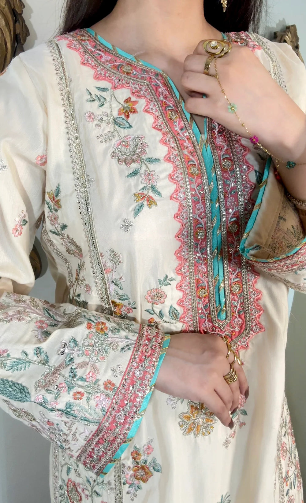 Close-up of coral scalloped embroidered neckline with aqua satin trim and gold zari on ivory viscose formal shirt
