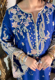 Model wearing embroidered blue kaftan suit showing floral embroidery detail at the neckline