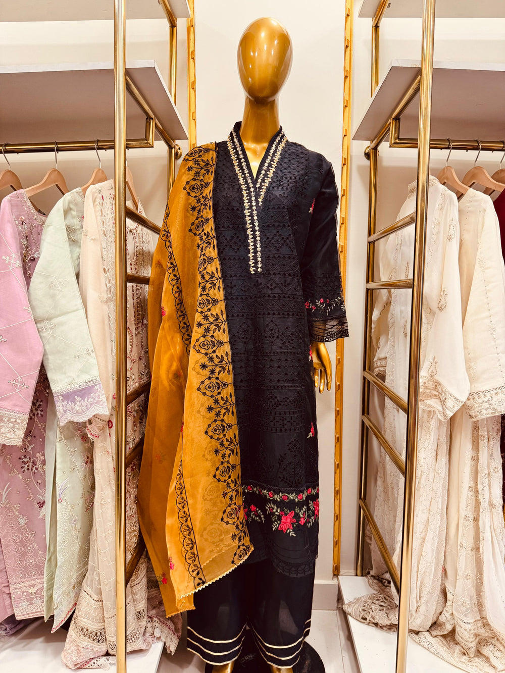 a black embroidered Oraganza outfit with a yellow dupatta in a clothing store.