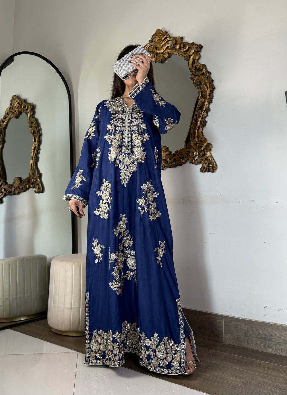 Full-length view of a model showcasing a stitched royal blue raw silk maxi dress with high side slits and a silver-embellished metallic clutch.