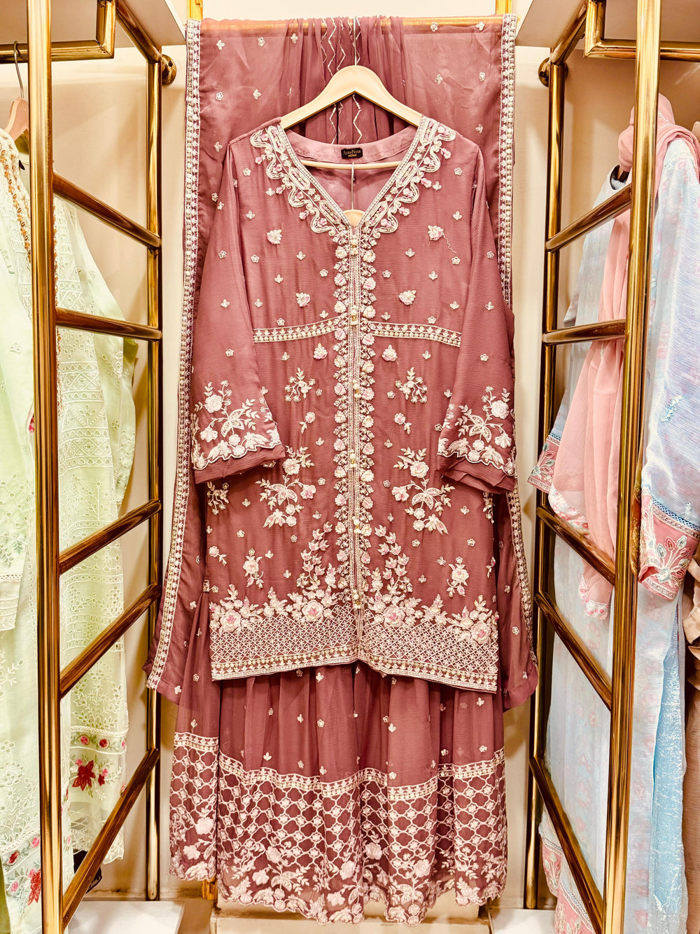 Pink embroidered traditional outfit on a hanger with a blurred background